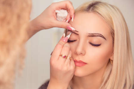 Changing the shape of the brows. Stylist drawing the eyebrows with dark pencil. Micropigmentation...