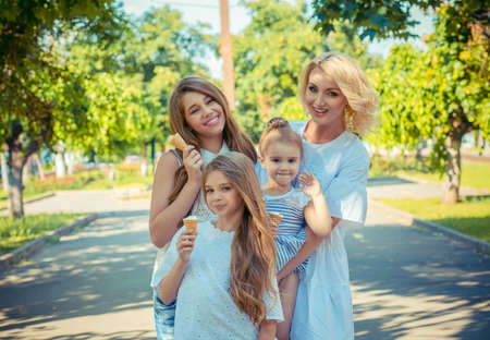 Happy family of mother with three daughters eating ice cream isolated in city center park background