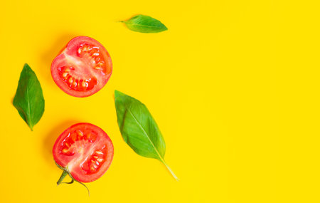 Healthy food and dieting concept. Red cherry tomatoes and oregano leaves isolated on yellow color studio background with copy space. Flat lay, view from top.の写真素材