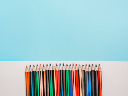 Back to school, education concept. Multicolored rainbow color pencils isolated on white and blue color studio background with copy space. Flat lay, view from top.の写真素材