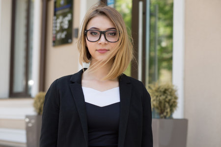 Serious woman looking at you camera near office building outsideの写真素材