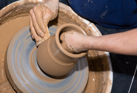 Man hands making ceramic pot vase on the pottery wheel. Concetration at work while shaping the vase.の写真素材