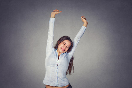 Happy smiling young woman stretching her arms wearing formal blue shirt stretching isolated on gray background.の写真素材
