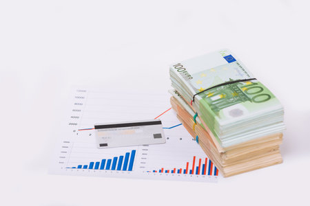 Stack pile of european money, Euro cash currency on a graphic chart and a pen on it isolated on white background. Savings for a investing in stock market, credit for business conceptual image.の写真素材