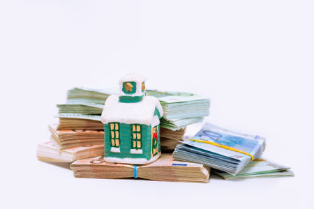 Stack pile of european money, Euro cash currency and a home on it isolated on white background. Savings for a new home, real estate property mortgage conceptual image.の写真素材