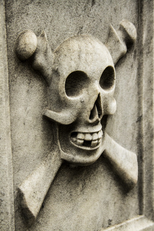 skull and cross bones on lateral of building in cementeryの写真素材