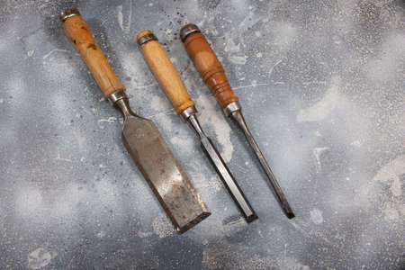 three Chisel isolated on rustic background. Used tool with rubber handle. Instrument for carpenter.の写真素材