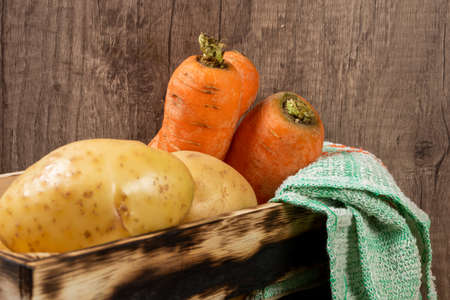 old Wooden box filled fresh potatoes and carrots