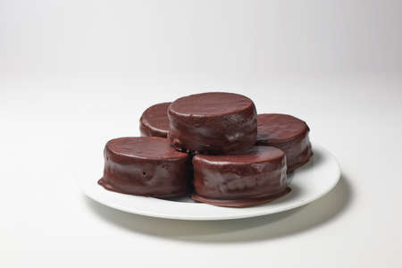Typical Argentine chocolate alfajores filled with dulce de leche on a plate on white background