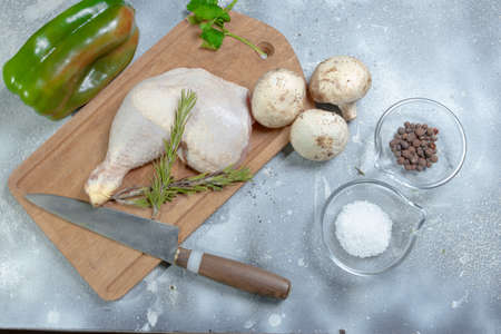 Raw chicken legs with rosemary and spices on a cement and black wooden background. Top view. Free...