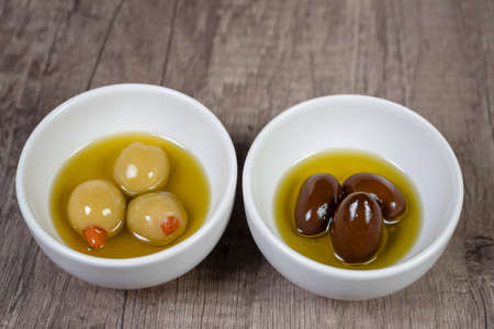 Bowls with green and black olives on wooden table top views