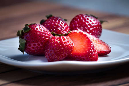 Strawberries on a white square plate on a wooden table in a rustic setting. close up view