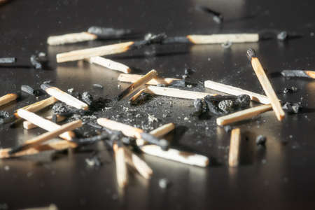 Used wooden matches with the remains of ashes on a black board. Selective focus. Hight contrast.の写真素材