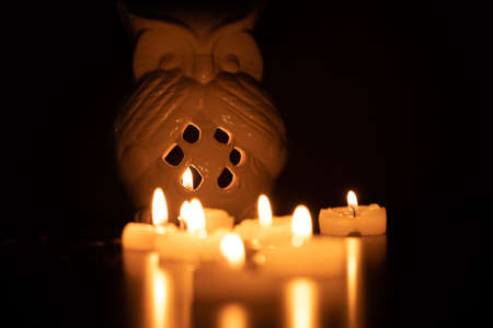 owl-shaped lantern and candles on a black table with subtle reflection and a black background. Selective focus and negative spaceの写真素材