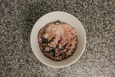 Small raw octopus inside a white slab bowl. granite background.の写真素材
