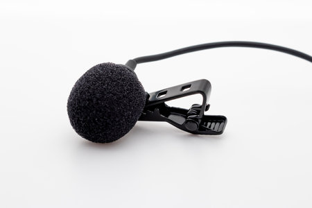 Lavalier or lapel microphone on a surface, very close-up. The details of the grip clip or bra and the sponge against the wind are visible.の写真素材
