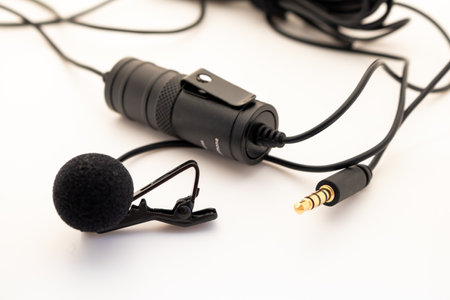 Lavalier or lapel microphone on a colored surface, very close-up. Details of the grip clip or...