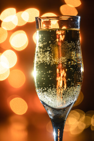 Close-up of a glass of champagne with candlelit background in a romantic setting.の写真素材