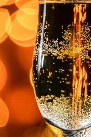 Close-up of a glass of champagne with candlelit background in a romantic setting.の写真素材