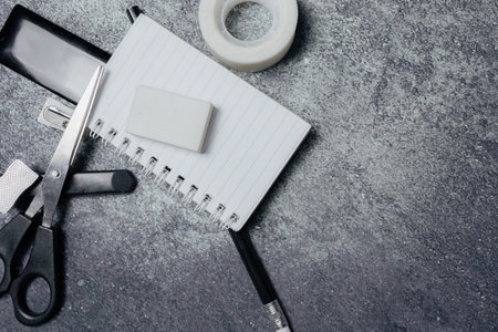 Small notebook, black pencil, eraser and other stationery on a rustic surface. Work items concept.の写真素材