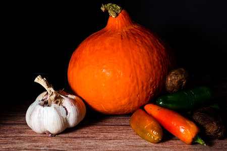 Uchiki Kuri or Red Kuri squash with peppers and garlic in a still life. Natural nutrition concept.の写真素材