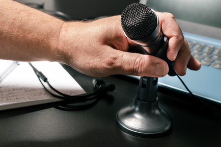 A man's hand accommodating a small desktop microphone before a virtual conference. Modern style, Communication and conference concept.の写真素材