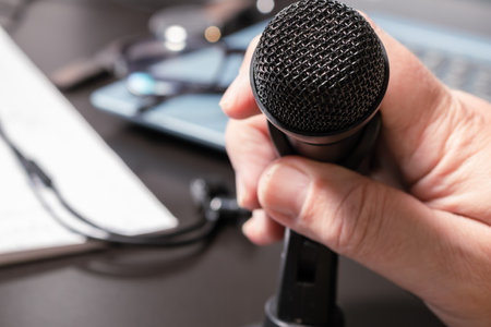 A man's hand accommodating a small desktop microphone before a virtual conference. Modern style, Communication and conference concept.の写真素材