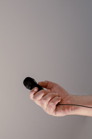 A mans hand holding a black microphone. Concept of communication, interviews, virtual dialogues.の写真素材