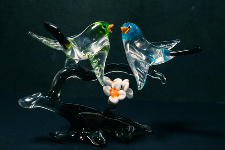 Pair of glass birds on a gray glass branch made in Murano, Italy. Black background.の写真素材