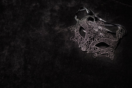 Venetian black woman mask, alone on a black surface. Concept of romantic mysteryの写真素材