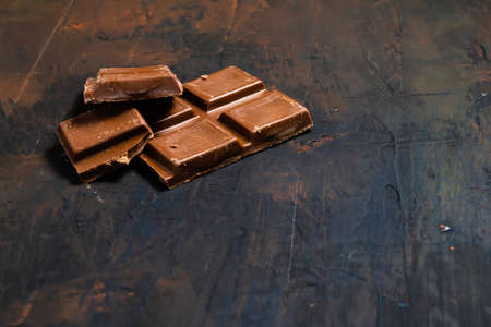 Tablet pieces of dark chocolate on a dark and industrial surface.の写真素材