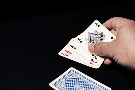 Poker of aces on a black surface.