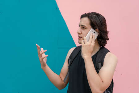 Young Latino man talking on the smartphone trying to explain an important topic.