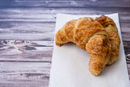 A croissant on a white napkin on a wooden table.の写真素材