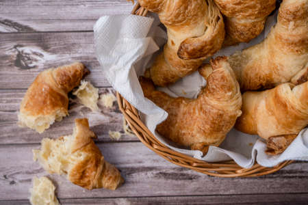 Croissants in a pan or bread basket and Croissants parts and crumbs on the table.の写真素材
