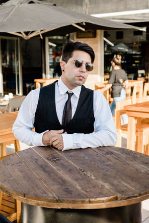 Young Latino entrepreneur at a high table in the outdoor area of a bar.の写真素材