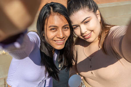 Two girl friends taking a selfie with their cell phone. Technology concept