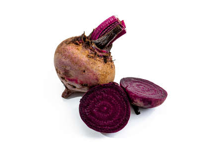 Whole leafless raw red beet root and a beet cut in half on a white surface. Fresh vegetables concept.の写真素材