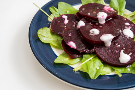 Beet and chicory salad with garlic aioli on a plate on a white marble background. Fresh and healthy...