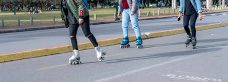 Close-up three young women rollerblading on the public highway in a park. Healthy and natural life...
