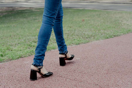 Woman's legs with shoes and pants walking on a path in a public park.の写真素材