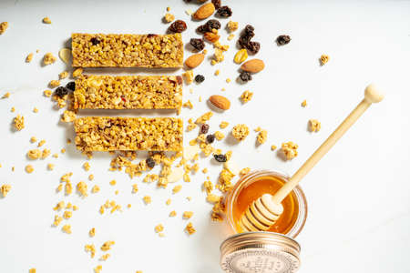 Aerial view of granola or cereal bars with dried fruits and raisins with a jar of natural honey on a...