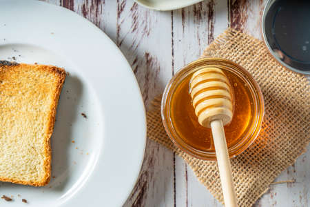Preparing a healthy breakfast with a toast with butter and pure organic honey from bees. Healthy...
