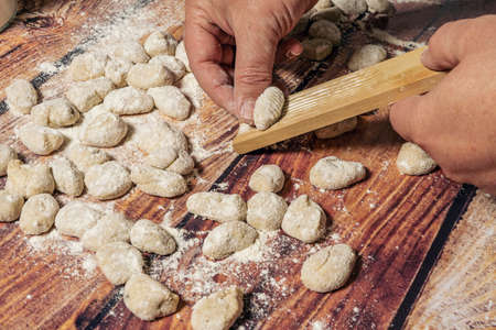 Chef passing the gnocchi through a manual gnocchi maker to give the classic ribbed shape to each piece. Homemade cookingの写真素材