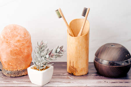 Wooden shelf in a bathroom with decorative elements such as the humidifier and the salt lamp with...