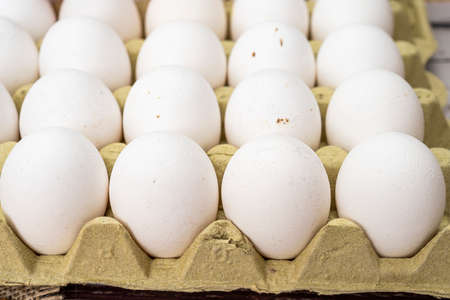 Exploded partial view of an egg carton container with organic white chicken eggs.