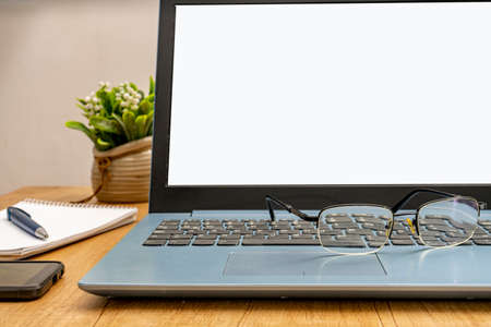 Normal view of an open laptop, a pair of glasses on the keyboard ready to work from home. Technology...