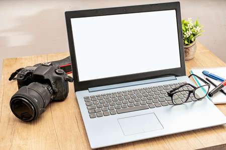 High View of an open laptop with a reflex camera and a pair of glasses on the keyboard ready to work...