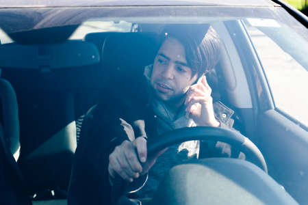Man talking on cell phone while driving a car. Concept danger, road safety,の写真素材