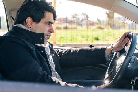 Young businessman driving a car. Transportation and land communications concept.